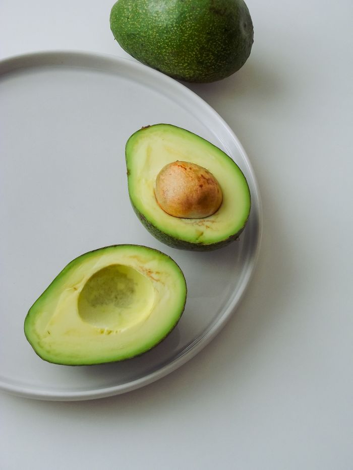 Sliced avocado halves on a ceramic plate, showcasing fresh, healthy produce.
